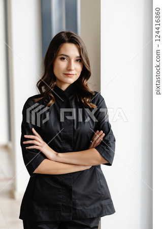 Young female doctor is standing in a hospital hall and looking at the camera Young female doctor is standing in a hospital hall and looking at the camera 124416860