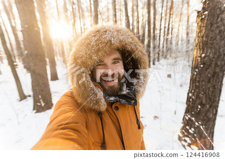 Man taking joyful winter selfie in snowy forest. Happiness, adventure and enjoying the beauty of nature during a cold season. Man taking joyful winter selfie in snowy forest. Happiness, adventure and enjoying the beauty of nature during a cold season. 124416908