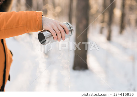 Hot drink poured from thermos into winter forest air. Contrast between warmth and cold, highlighting seasonal rituals and sensory moments. Copy space 124416936