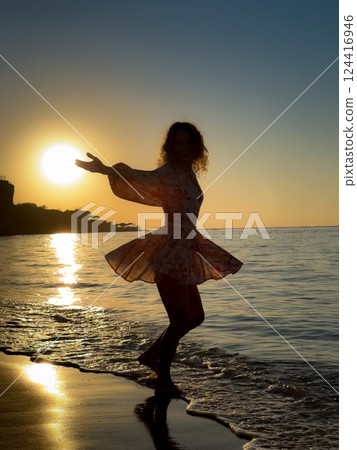 Silhouette of young woman dancing at the sandy beach 124416946