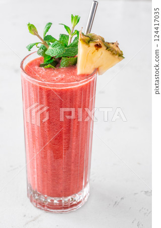 Fruit smoothie with cherry, banana, pineapple, mint garnish, and pineapple wedge 124417035
