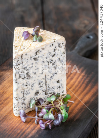 Wedge of Roquefort cheese resting on a rustic wooden cutting board 124417040