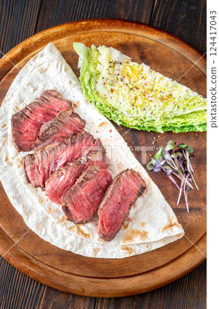Sliced medium-rare beef steak with tortilla and crisp nappa cabbage wedge 124417043