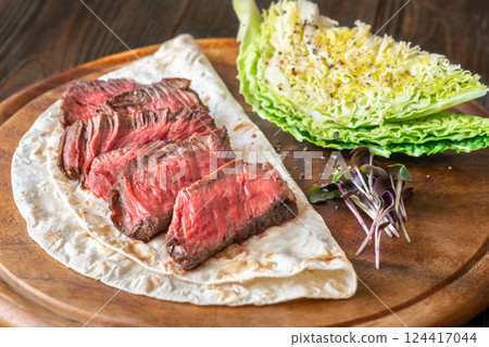 Sliced medium-rare beef steak with tortilla and crisp nappa cabbage wedge 124417044