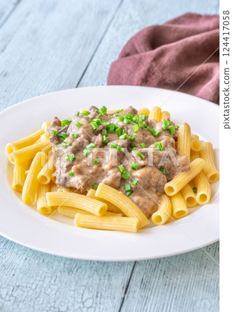 Beef stroganoff with rigatoni pasta, topped with fresh green onion garnish 124417058