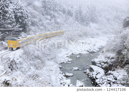 The Fukuchiyama Line Kounotori train racing through a snow-covered valley 124417106