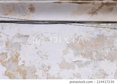 Aged wall with peeling paint and an exposed wire running horizontally across it Aged wall with peeling paint and an exposed wire running horizontally across it 124417230