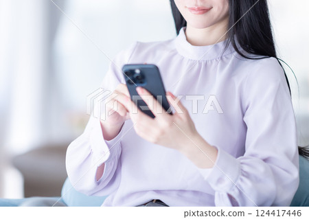 A young woman checking the stock prices of her NISA savings on her smartphone A young woman checking the stock prices of her NISA savings on her smartphone 124417446