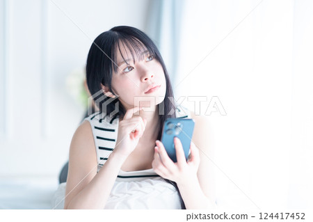 A young woman examining a smartphone 124417452