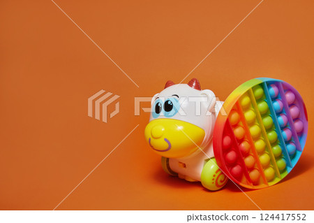 anti-stress toy pop it and toy cow on orange background with copy space 124417552