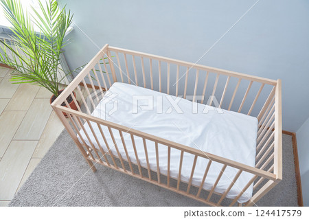 Baby bed top view. A bright room green potted flower and a carpeted floor. 124417579