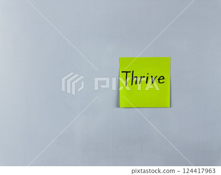 Sticky note with the word Thrive written on it, placed on white background. Ideal for illustrating themes of success, growth, and flourishing in various aspects of life. Great for concept creation 124417963