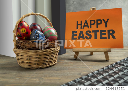 Wooden basket and a nest filled with colorful decorated easter eggs and happy easter greetings on the table. Concept of celebrating the easter holiday 124418251