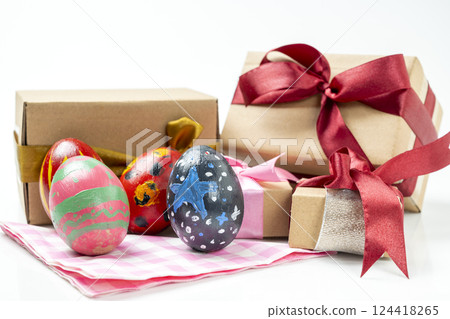 Colorful decorated easter eggs with gift boxes on a checkered square cloth isolated over a white background. Concept of celebrating the easter holiday Colorful decorated easter eggs with gift boxes on a checkered square cloth isolated over a white background. Concept of celebrating the easter holiday 124418265