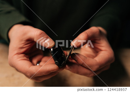 Professional technician male carefully opening smartwatch to replace battery, demonstrating intricate process of device repair. Concept of process electronic device maintenance. 124418937