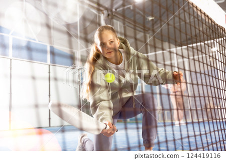 Teenager girl plays paddle. View through grid 124419116