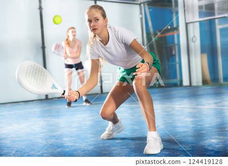 Padel game - teen girl actively kicks ball during a padel game Padel game - teen girl actively kicks ball during a padel game 124419128