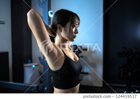 Cool woman tying her hair while working out at the gym Power rack Bench press Muscle training girl 124419517