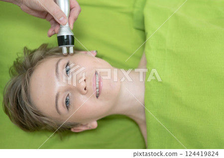 Top view of Caucasian woman undergoing radio wave RF lifting procedure in beauty salon. Top view of Caucasian woman undergoing radio wave RF lifting procedure in beauty salon. 124419824