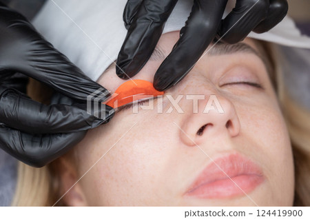 The master lays down the roller before the eyelash lamination procedure.  124419900