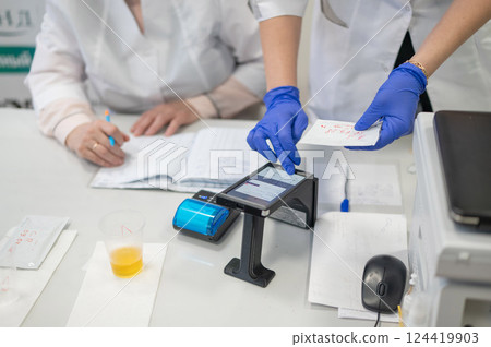 A narcologist tests urine for drugs using an electronic device.  124419903