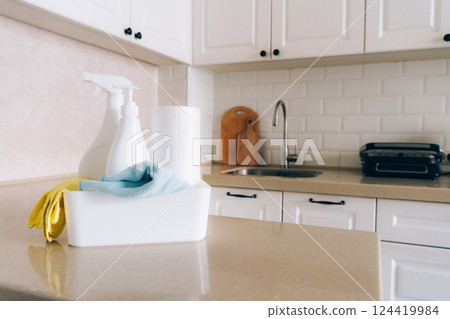 Pristine white kitchen with cleaning supplies on countertop 124419984