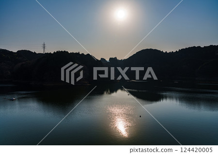 Wind blowing across the lake surface. Spring 2025 at Nara Nunome Dam. The sun floating in the spring hazy sky. 124420005