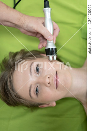 Top view of Caucasian woman undergoing radio wave RF lifting procedure in beauty salon. Top view of Caucasian woman undergoing radio wave RF lifting procedure in beauty salon. 124420062