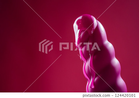 Lube pouring on pink dildo on pink background.  124420101