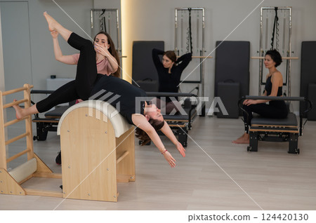 Three women doing Pilates on a reformer and a Pilates barrel.  124420130