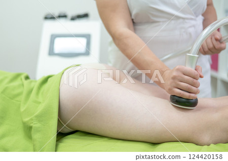 Caucasian woman on hardware anti-cellulite massage. Thigh cavitation procedure. 124420158