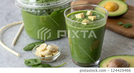 Homemade Smoothie A closeup of a clear glass filled with a vibrant green smoothie made from spinach avocado and banana p beside a prepackaged smoothie cup.. Homemade Smoothie A closeup of a clear glass filled with a vibrant green smoothie made from spinach avocado and banana p beside a prepackaged smoothie cup.. 124420466