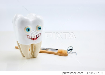 Happy Tooth. A smiling tooth sculpture beside dental tools Happy Tooth. A smiling tooth sculpture beside dental tools 124420719