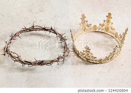 A crown of thorns lies beside an ornate golden crown 124420804