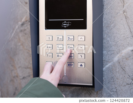 Person entering security code on keypad access control system. 124420872