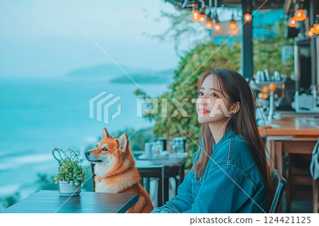 一位女士和她的柴犬在俯瞰大海的露臺上享受咖啡時光 124421125