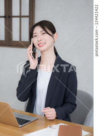 一位年輕女商人在辦公室工作，用智慧型手機聊天 124421422