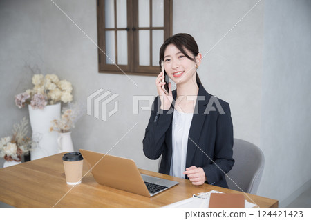 一位年輕女商人在辦公室工作，用智慧型手機聊天 124421423