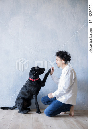 A man playing with a large dog - high-five 124422053
