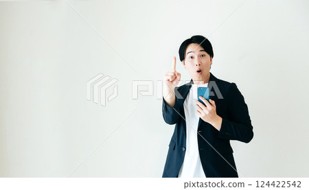 A businessman holding a smartphone and talking with a smile 124422542