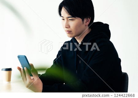 Young man looking at his smartphone by the window 124422668