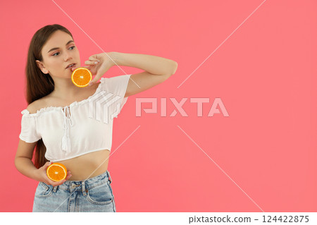 An attractive young girl holds oranges in her hands An attractive young girl holds oranges in her hands 124422875