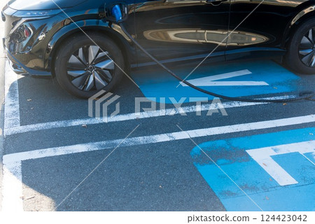 Electric car being charged at a service station on the highway 124423042