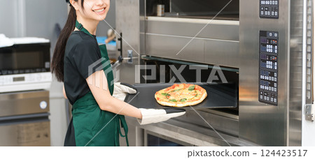 女廚師從烤箱拿出披薩 124423517