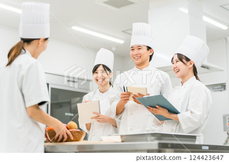A female instructor teaching at a chef seminar, vocational school, and employee training, and male and female students (in the food service industry) 124423647