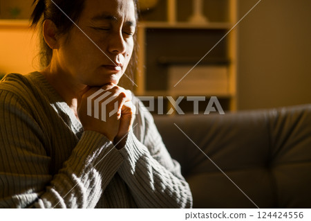 Christian religious woman praying at night sitting on couch in living dark room at home. Human person hands worship, Concept of praying to God. Female prayer with holy bible. Lady thanksgiving night Christian religious woman praying at night sitting on couch in living dark room at home. Human person hands worship, Concept of praying to God. Female prayer with holy bible. Lady thanksgiving night 124424556