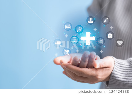 Woman hand holding plus with healthcare medical icon on blue sky background. Health insurance health concept. Access to welfare health and copy space, benefit pharmacy, plan community treatment. 124424588