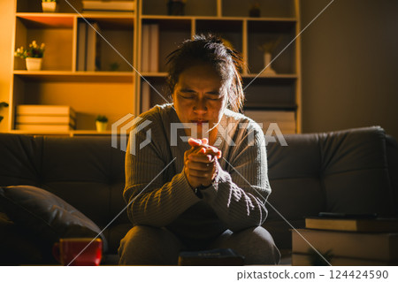 Christian religious woman praying at night sitting on couch in living dark room at home. Human person hands worship, Concept of praying to God. Female prayer with holy bible. Lady thanksgiving night 124424590
