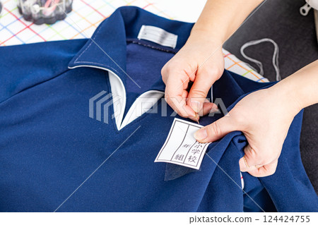 將姓名標籤縫在運動服上的手 124424755