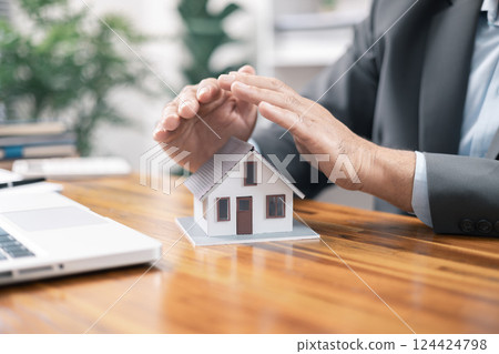 Insurance house concept. The insurance agent presents the hands protection model house. Make a contract for hire purchase and sale of a house. home insurance contracts, home mortgage loan concepts. 124424798